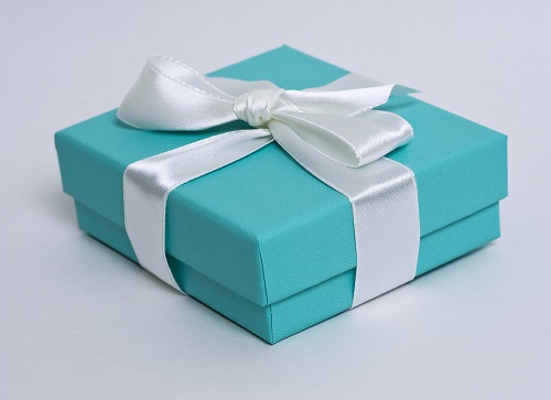 Turquoise Tiffany gift box with white ribbon on neutral background